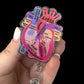 A hand holding a badge reel with an anatomical heart design, featuring labeled parts such as 'AORTA' and 'PULMONARY ARTERY'.