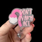 A badge reel with a pink and white design featuring text and a face silhouette, attached to a clear snap clip.