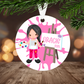 Decorative Christmas ornament with a  girl painting, hanging on a tree branch.