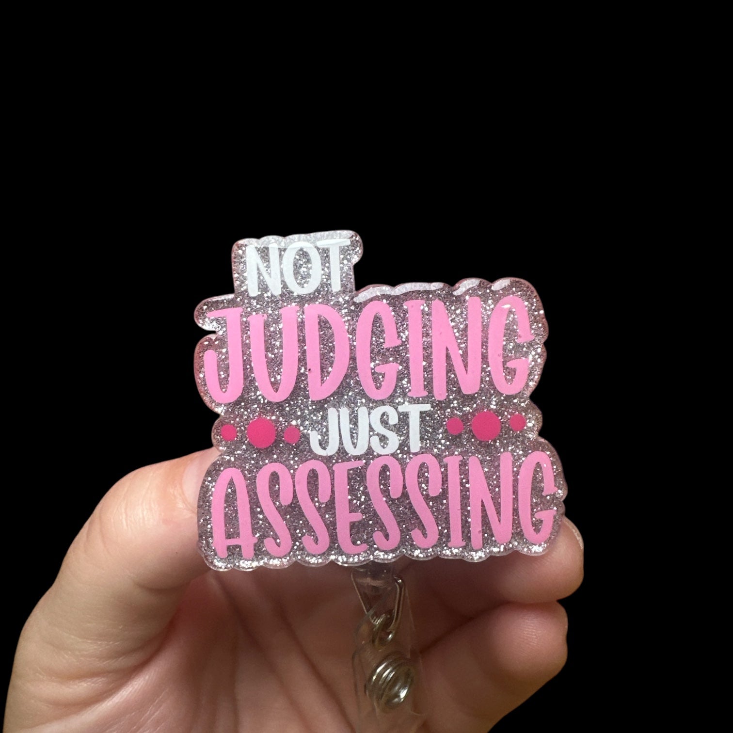 A badge reel with the phrase 'NOT JUDGING JUST ASSESSING"