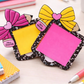 Two decorative post-it notes with colorful bows on a desk.