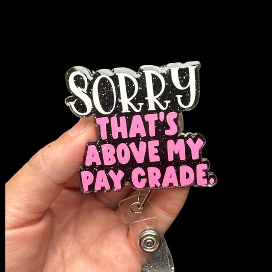 A badge reel with the phrase 'SORRY THAT'S ABOVE MY PAY GRADE' printed in black and pink on a clear reel.