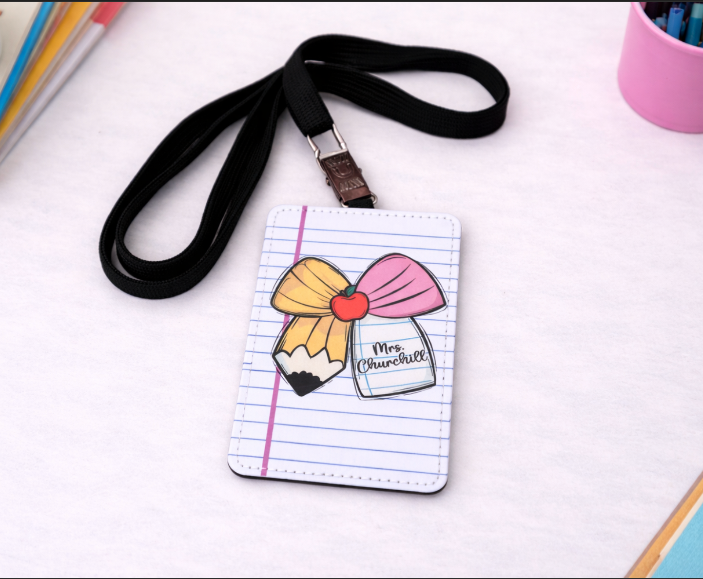 Notebook-style lanyard holder with a pencil and bow design 