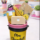 Yellow bucket filled with stationery items on a desk.