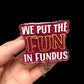 A pink badge reel with the text 'WE PUT THE FUN IN FUNDUS' in glittery gold and white letters.