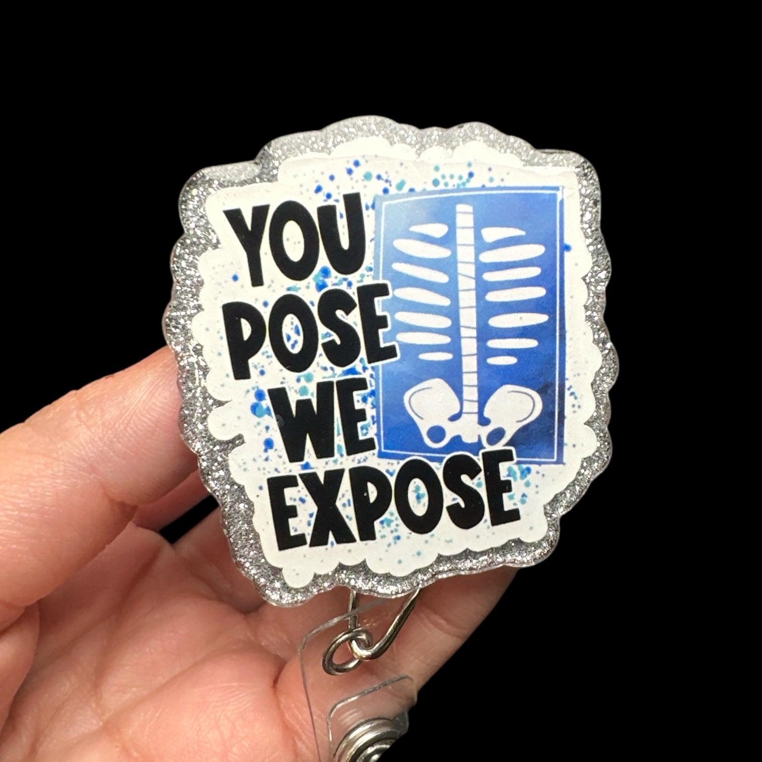 A badge reel with the text 'YOUPOSE WE EXPOSE' printed on it, featuring a blue and white color scheme