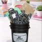 Black bucket filled with composition books and stationery items on a desk.