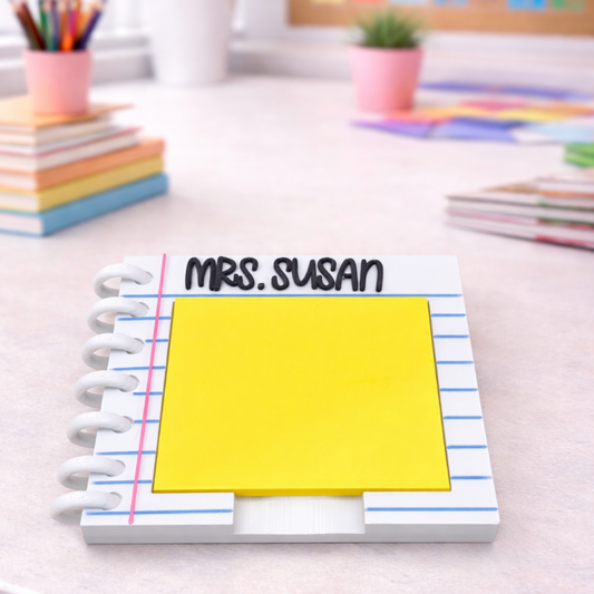 Notebook with a yellow sticky note on a desk with stationery items.